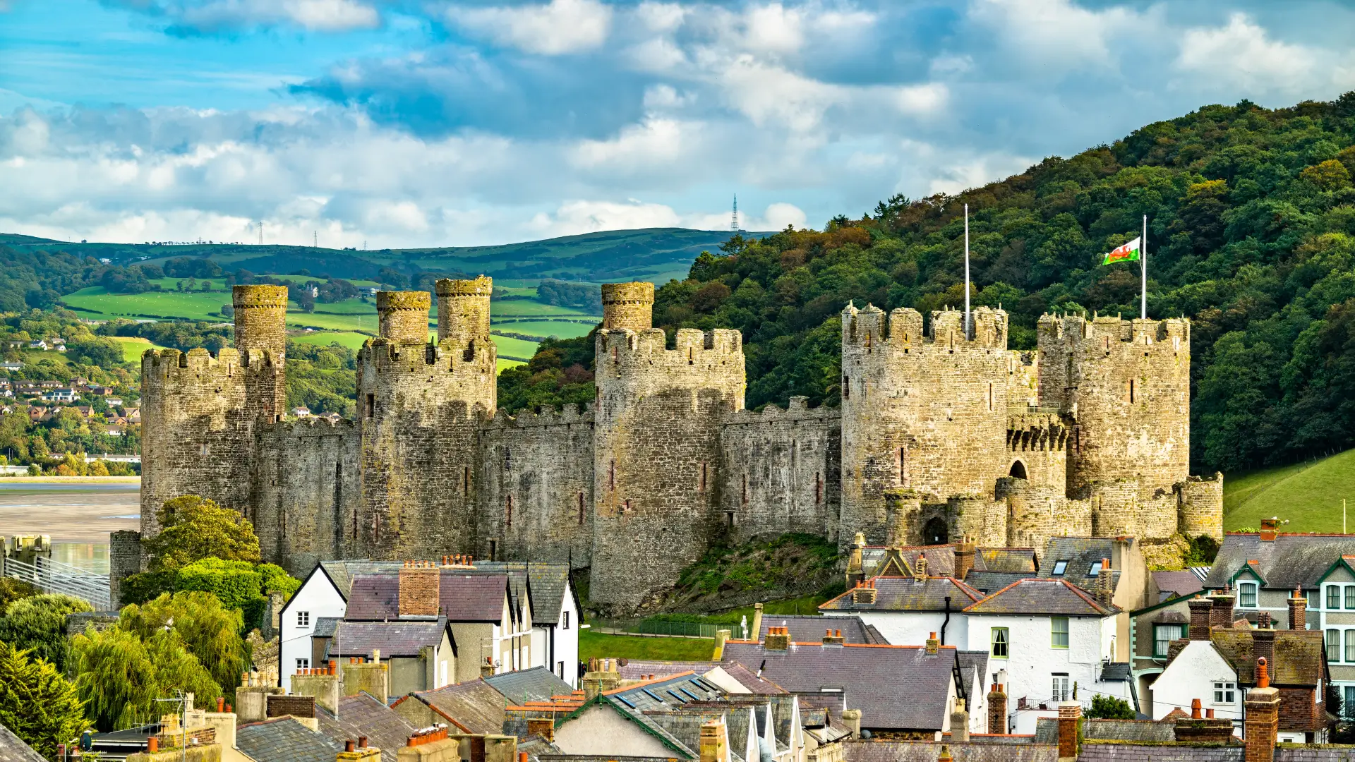 Historic stone castle surrounded by green countryside and village rooftops in the United Kingdom.