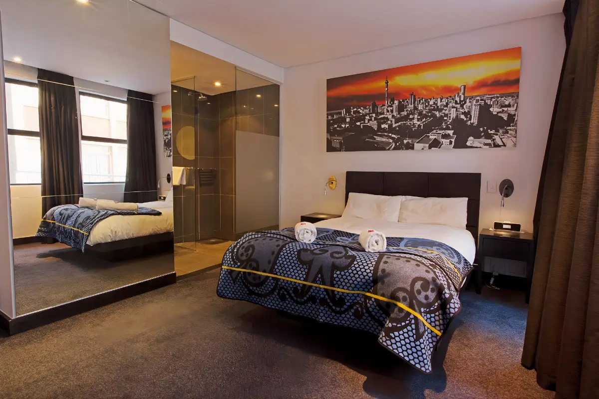 Hotel room at Once in Joburg with modern décor, city artwork, and warm lighting.