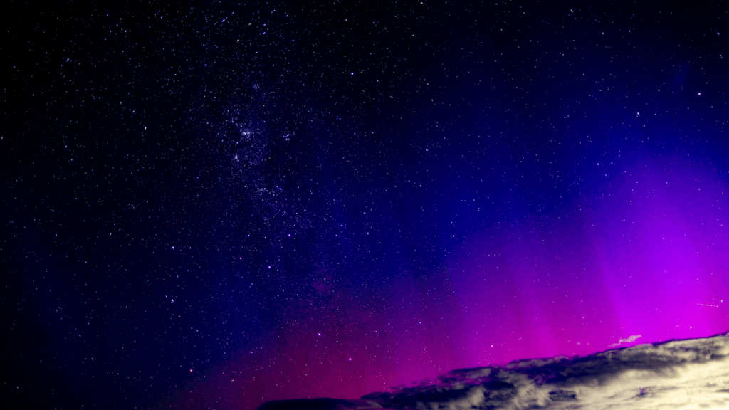 Purple and pink Aurora Australis glowing low on the horizon over New South Wales.