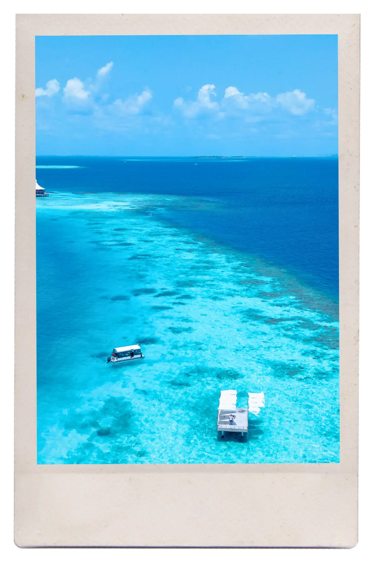 Turquoise waters of the Belize Barrier Reef with a small dock and boat floating above shallow coral.