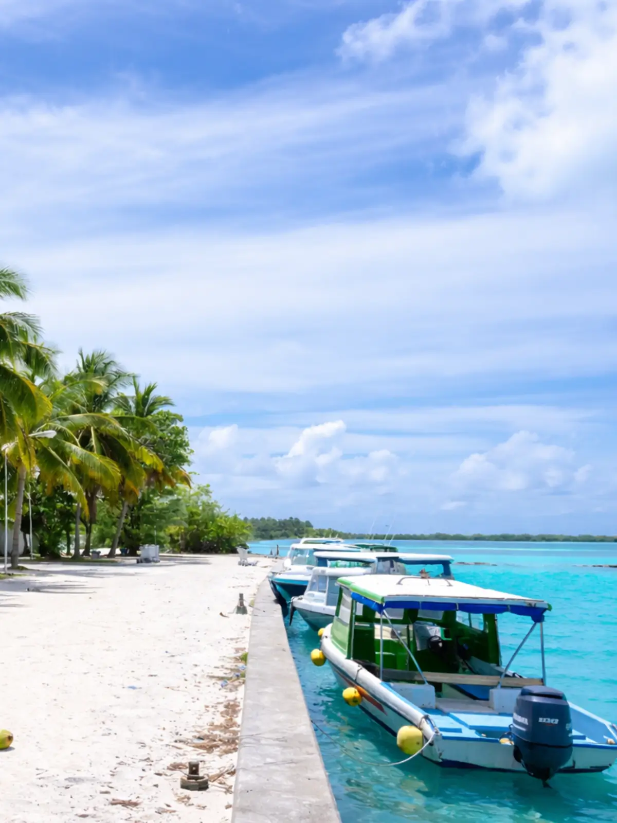 Small boats moored along a sandy beach with turquoise water in Belize.