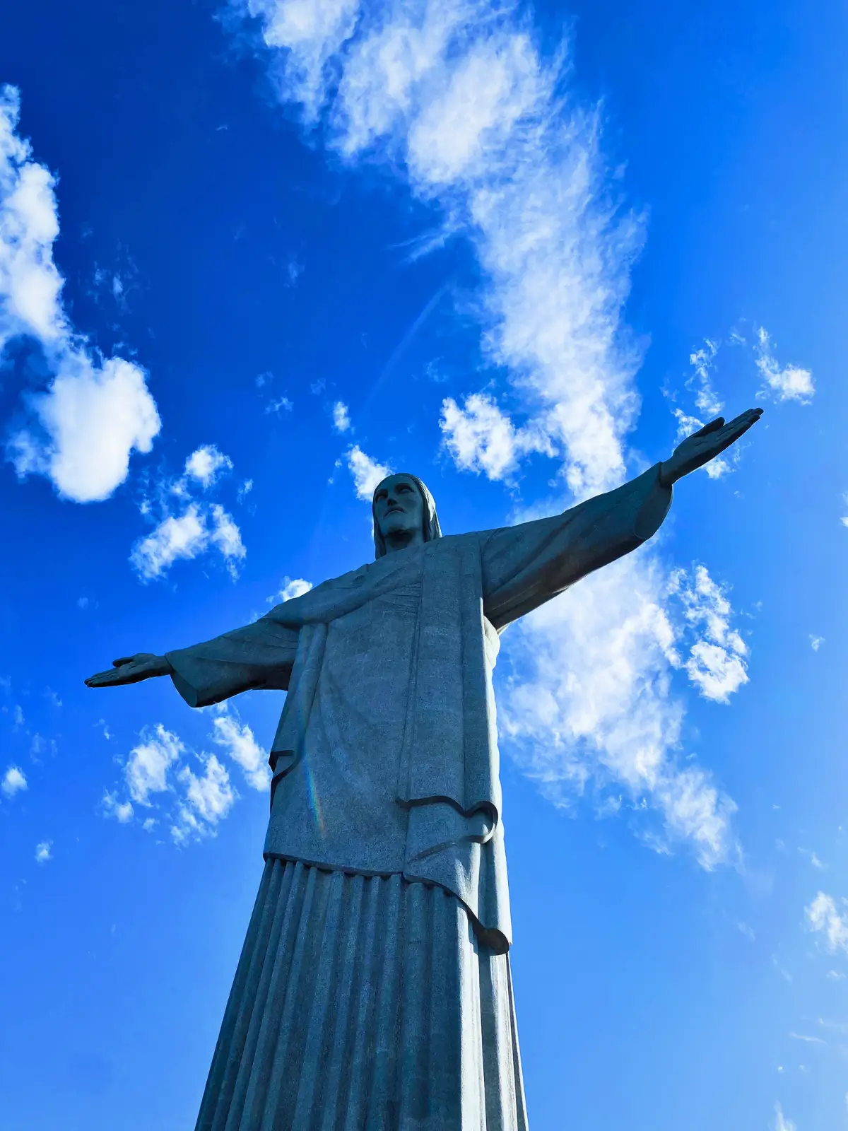 Christ the Redeemer statue in Rio de Janeiro against a blue sky.