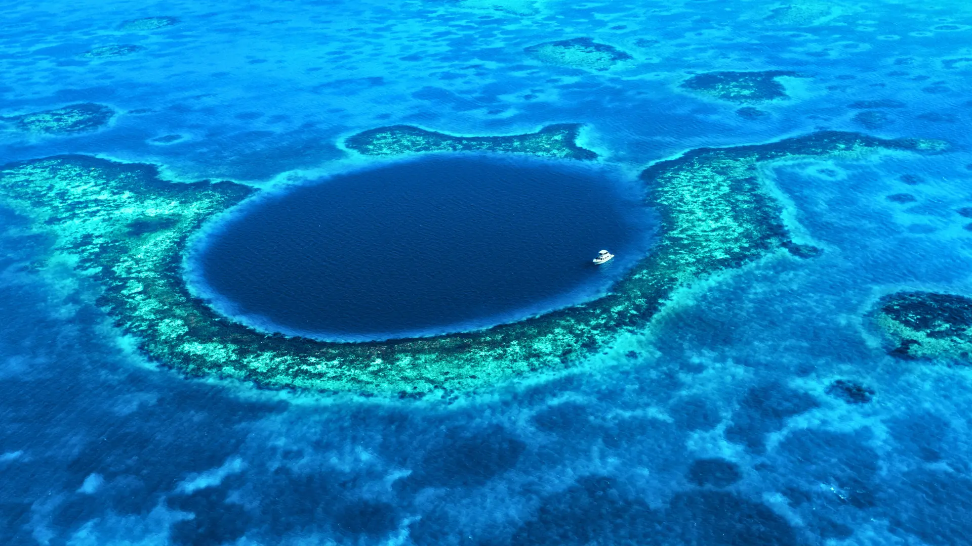 Aerial view of the Great Blue Hole surrounded by coral reef in Belize.