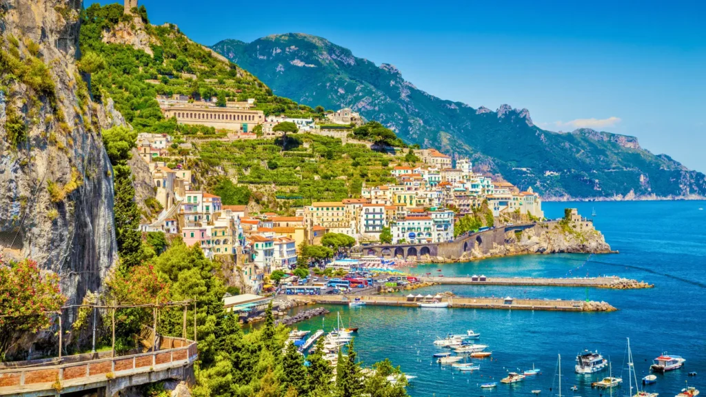 Amalfi Coast town in Italy overlooking the sea with boats and hillside buildings.