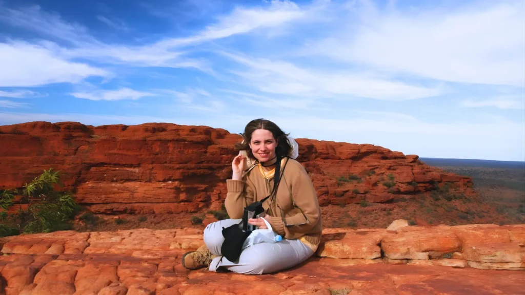 Manu sitting on red sandstone cliffs during the Kings Canyon Rim Walk in Australia.