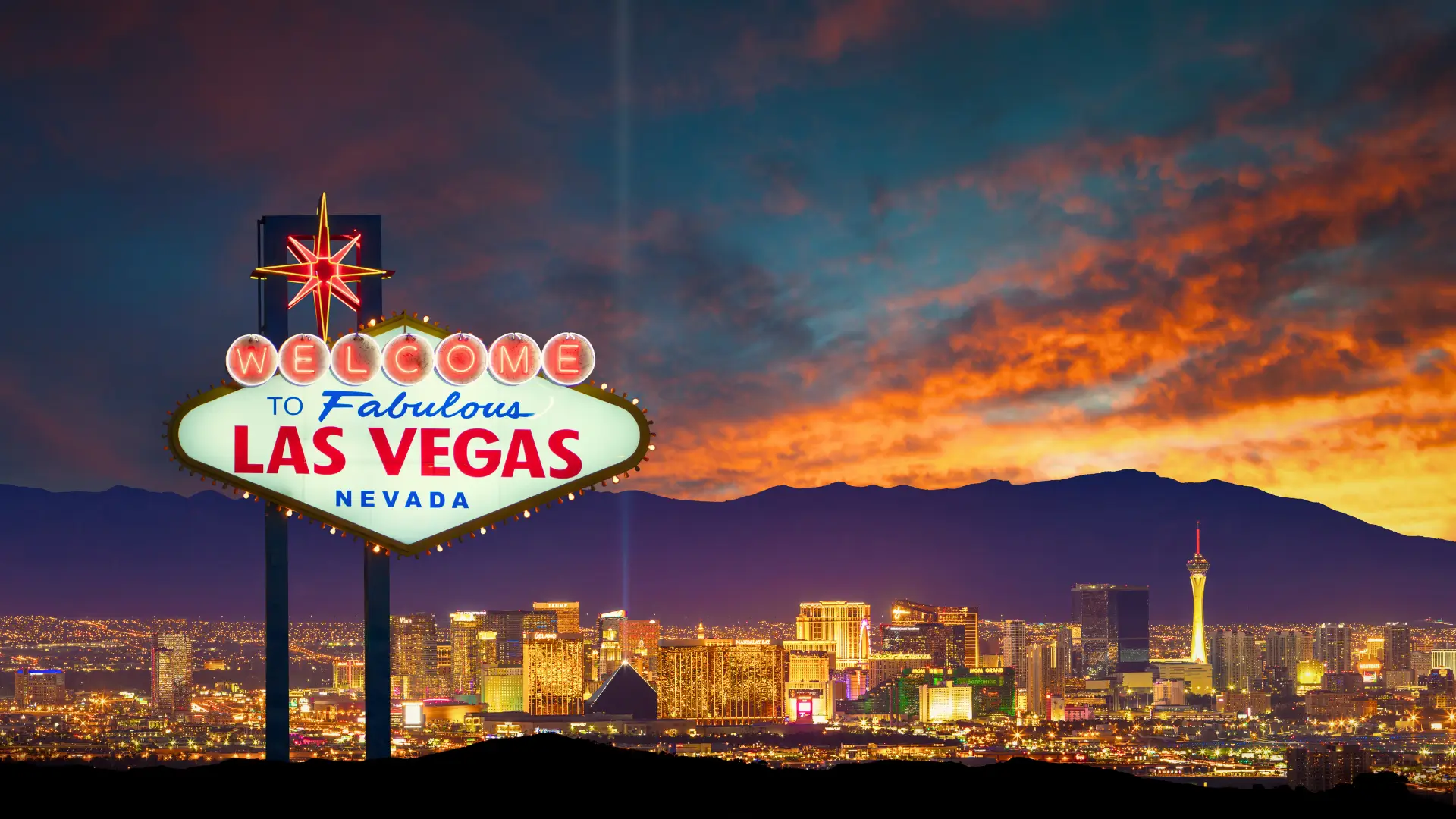 Welcome to Las Vegas sign with city skyline and mountains at sunset in Nevada, United States.