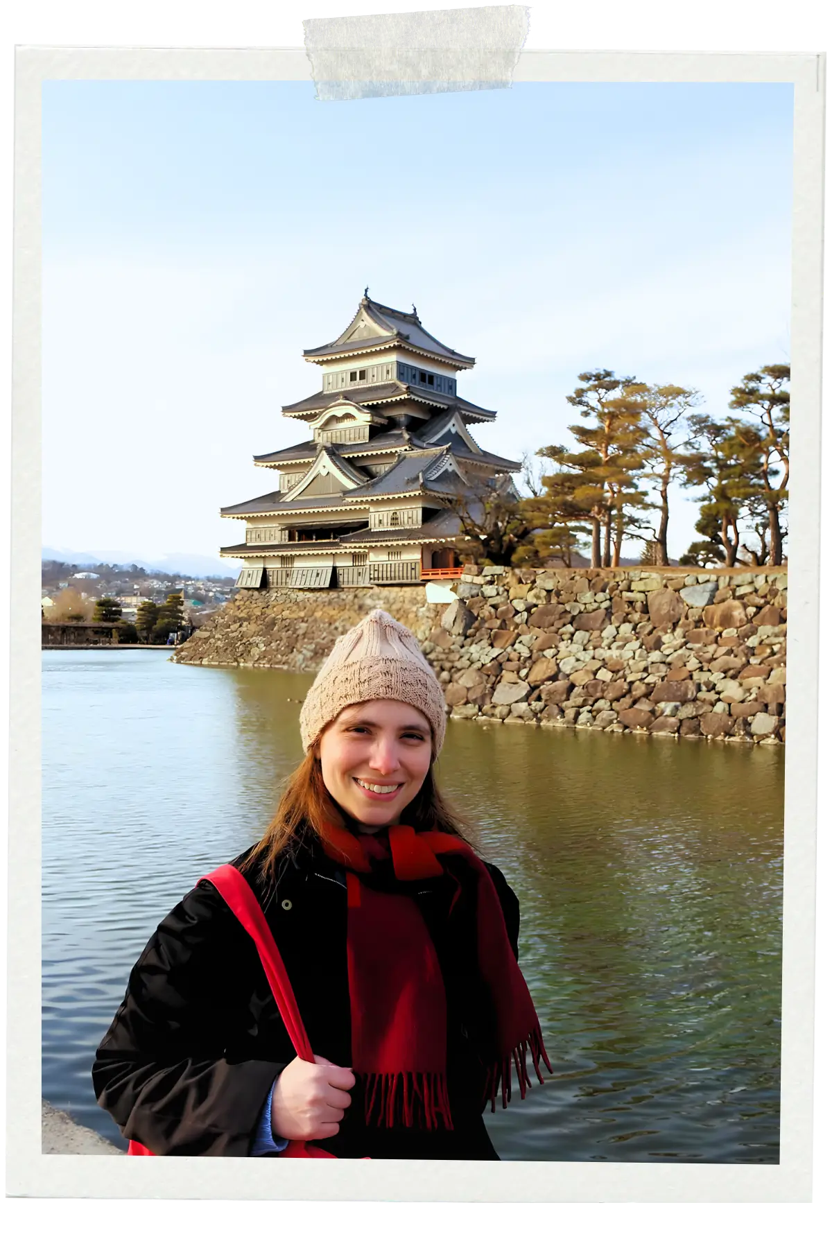 Manu standing by the water with Matsumoto Castle in the background in Japan.