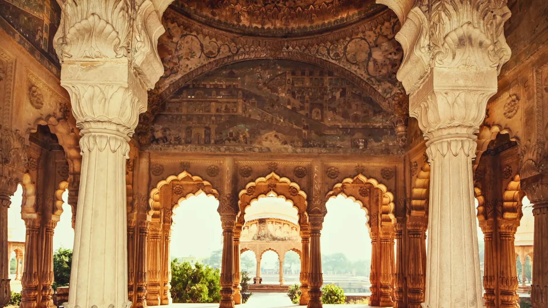 Ornate Mughal architecture with carved stone arches and columns inside a historic palace in India.