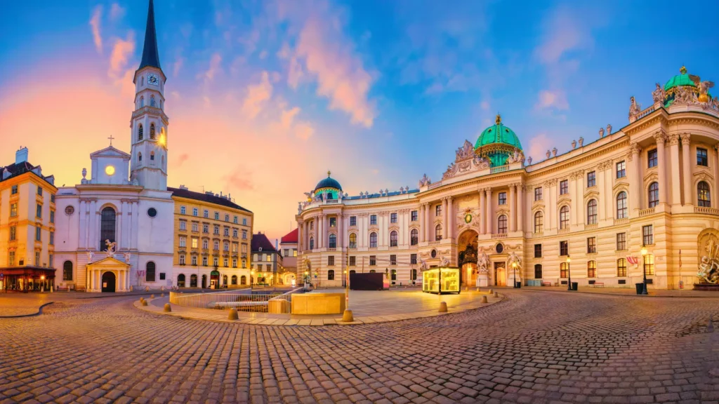 Wide view of Vienna’s Michaelerplatz showing the Hofburg Palace and historic buildings at dusk.