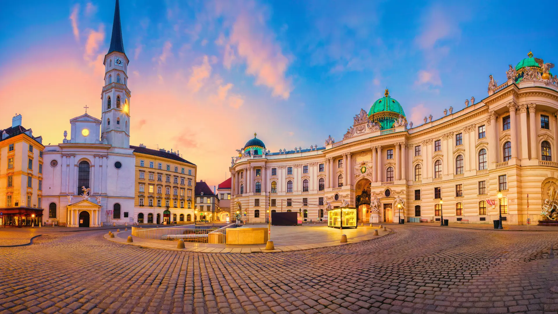 Wide view of Vienna’s Michaelerplatz showing the Hofburg Palace and historic buildings at dusk.