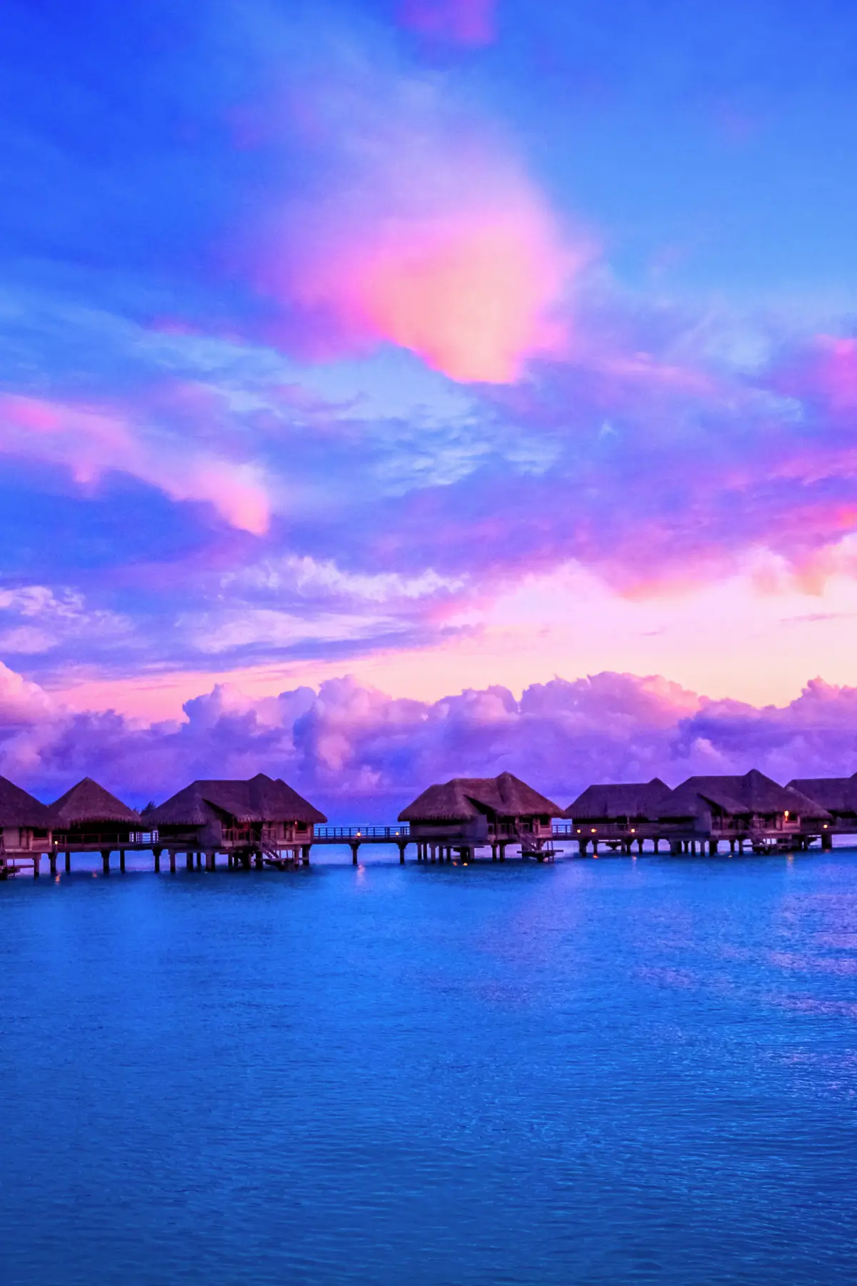 Romantic overwater bungalows in Bora Bora during a vibrant tropical sunset.