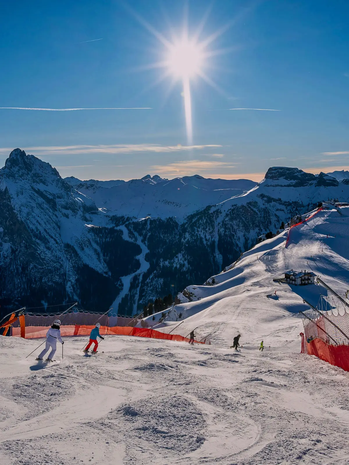 Skiers descending a snowy slope in Cortina d’Ampezzo with Dolomite mountain peaks.