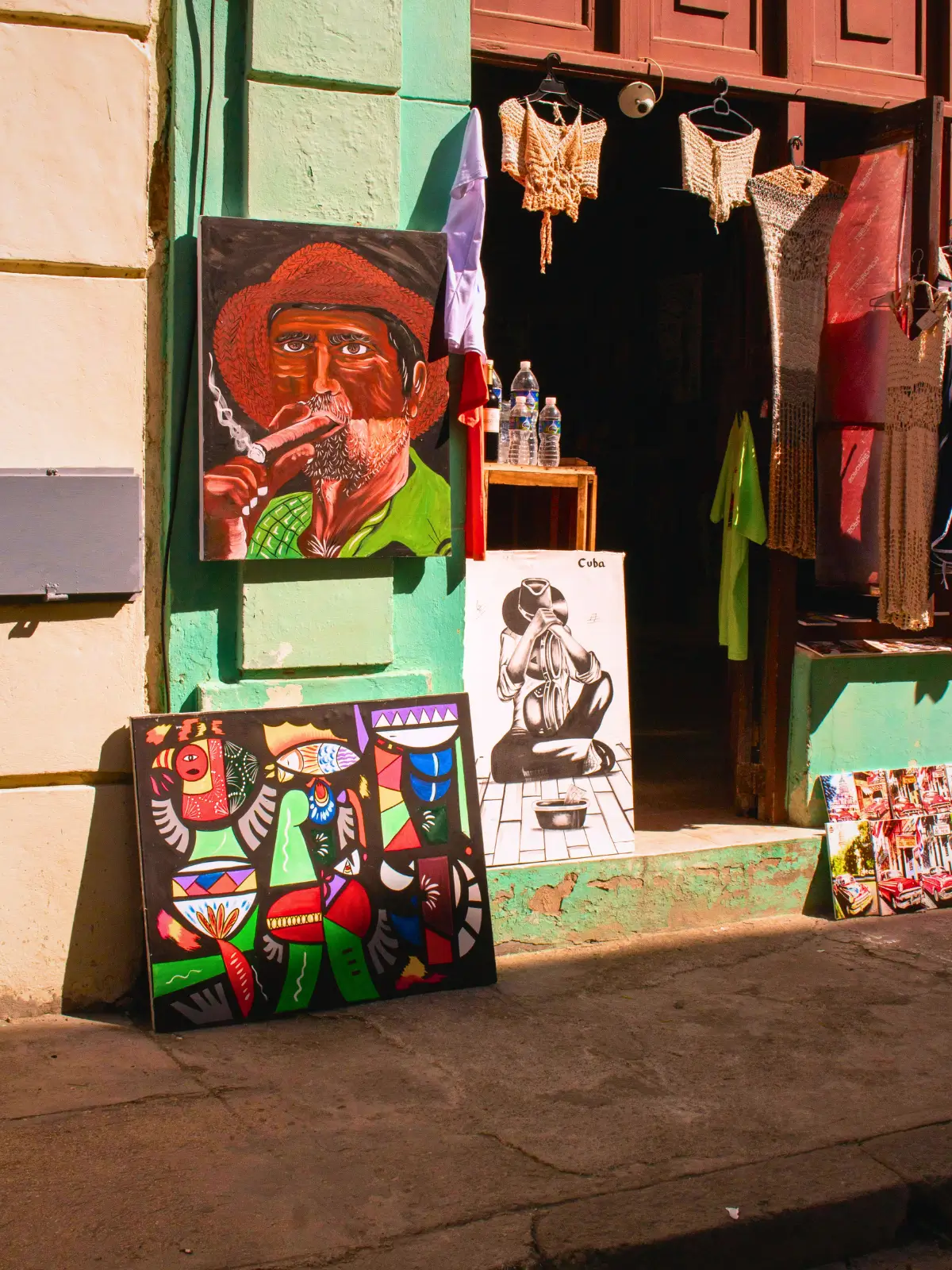 Colourful paintings displayed outside a small shop in a Cuban street.