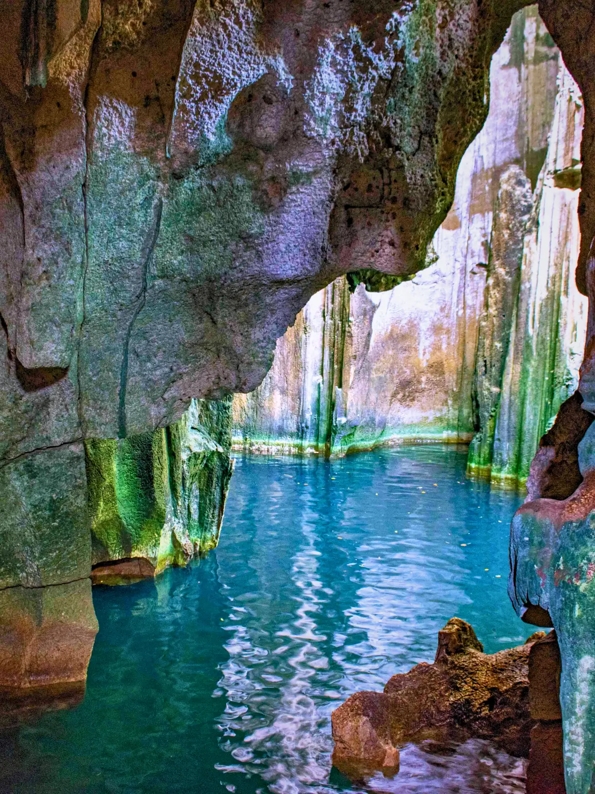 Clear blue water inside a natural rock pool surrounded by limestone walls.