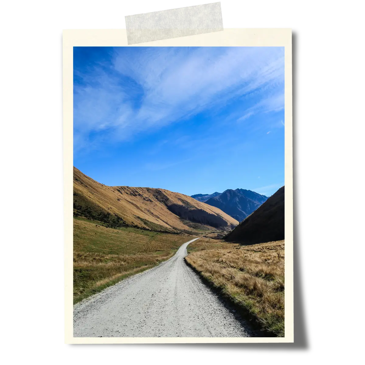 Gravel road winding through a mountain valley under a blue sky on New Zealand’s South Island.