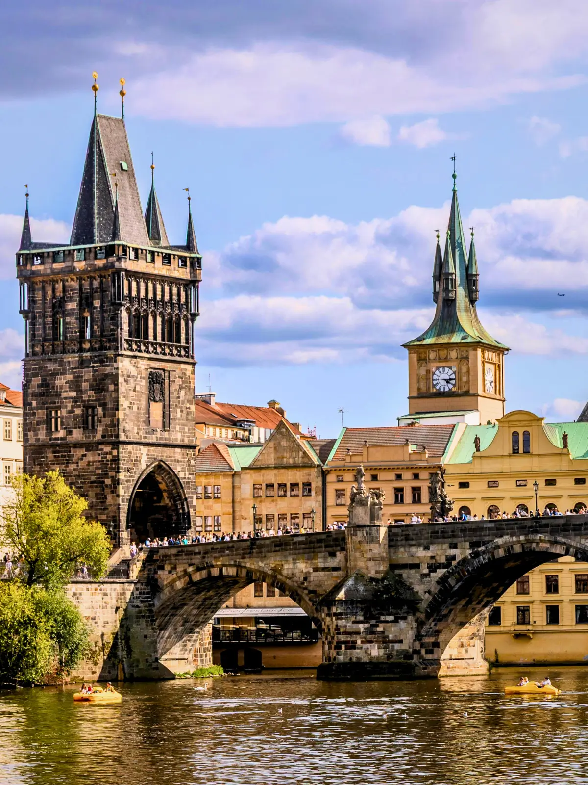 Charles Bridge with Old Town Bridge Tower and historic buildings along the Vltava River in Prague, Czech Republic.