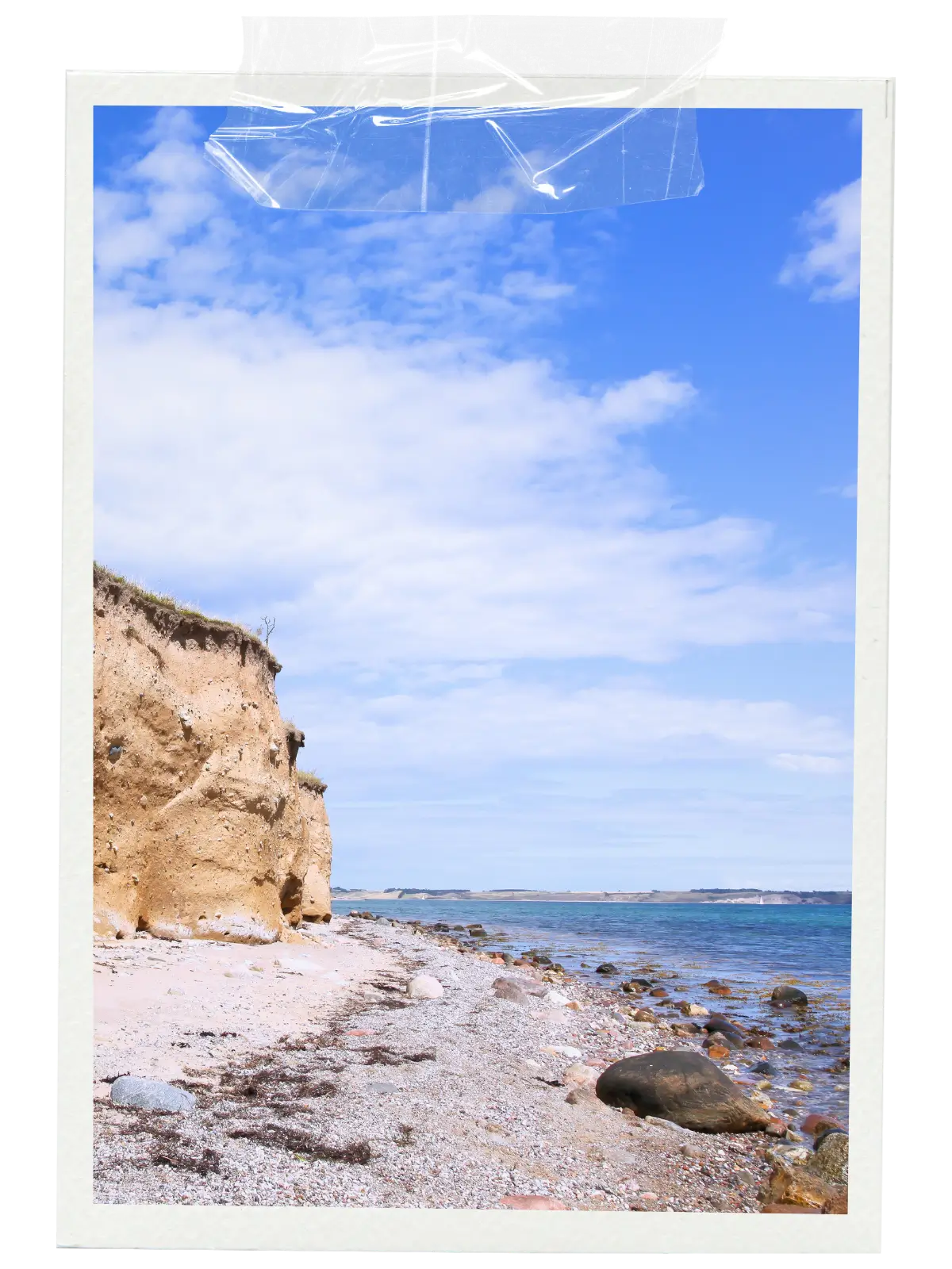 Rocky beach and coastal cliff along Denmark’s coastline under a bright blue sky.