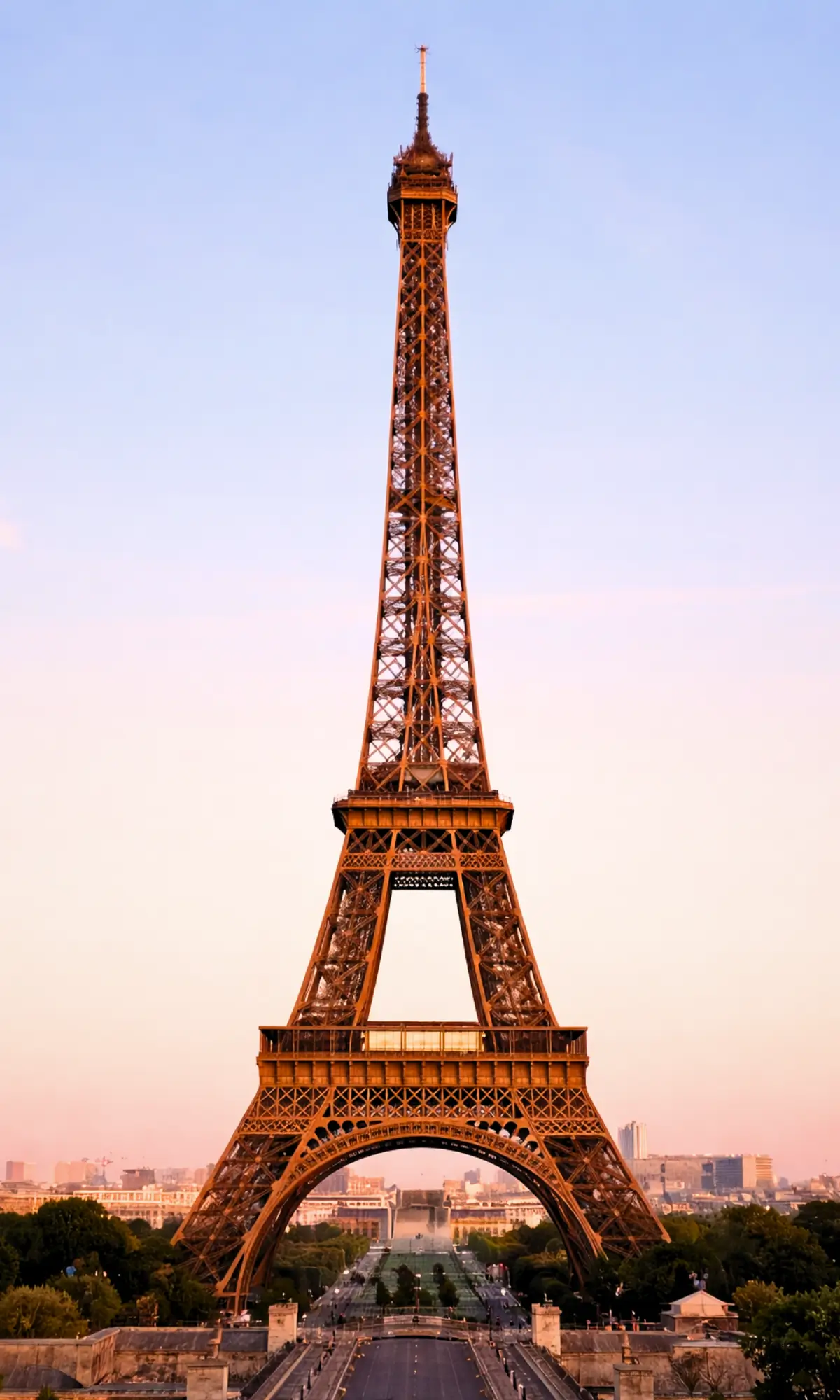 Eiffel Tower in Paris at sunset with city skyline and gardens below.