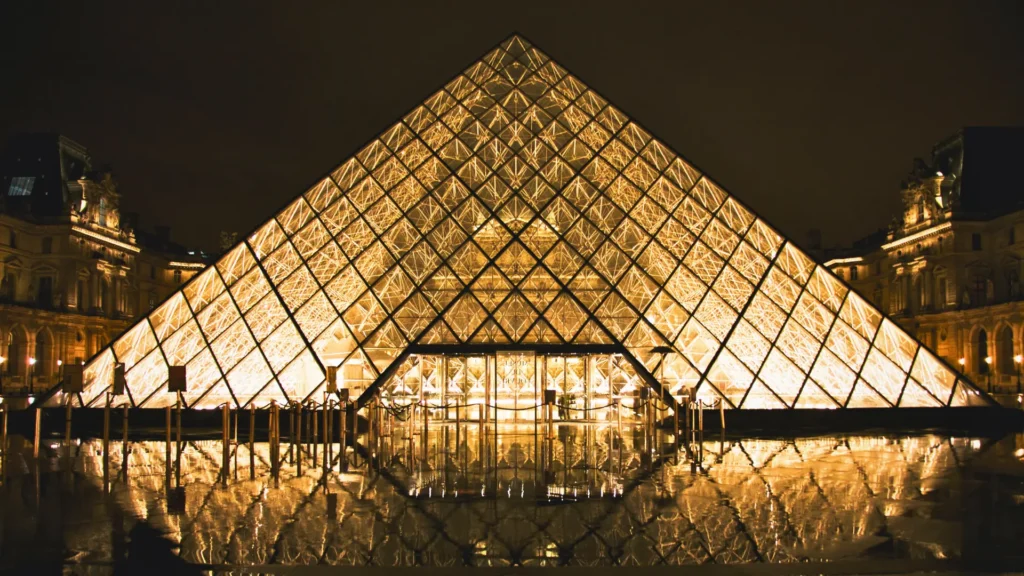 Louvre Pyramid illuminated at night in Paris.