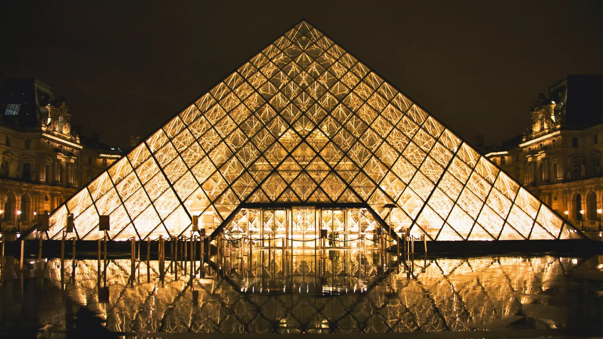 Louvre Pyramid illuminated at night in Paris.