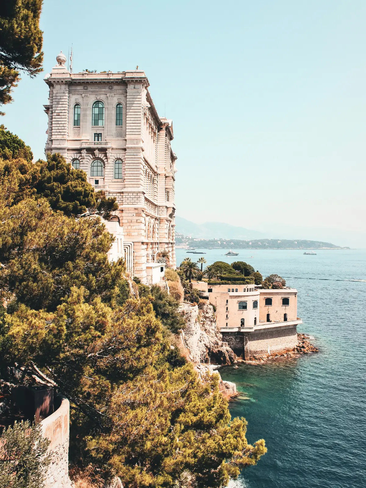 Oceanographic Museum of Monaco on a cliff overlooking the Mediterranean Sea with coastal views and boats in the distance.
