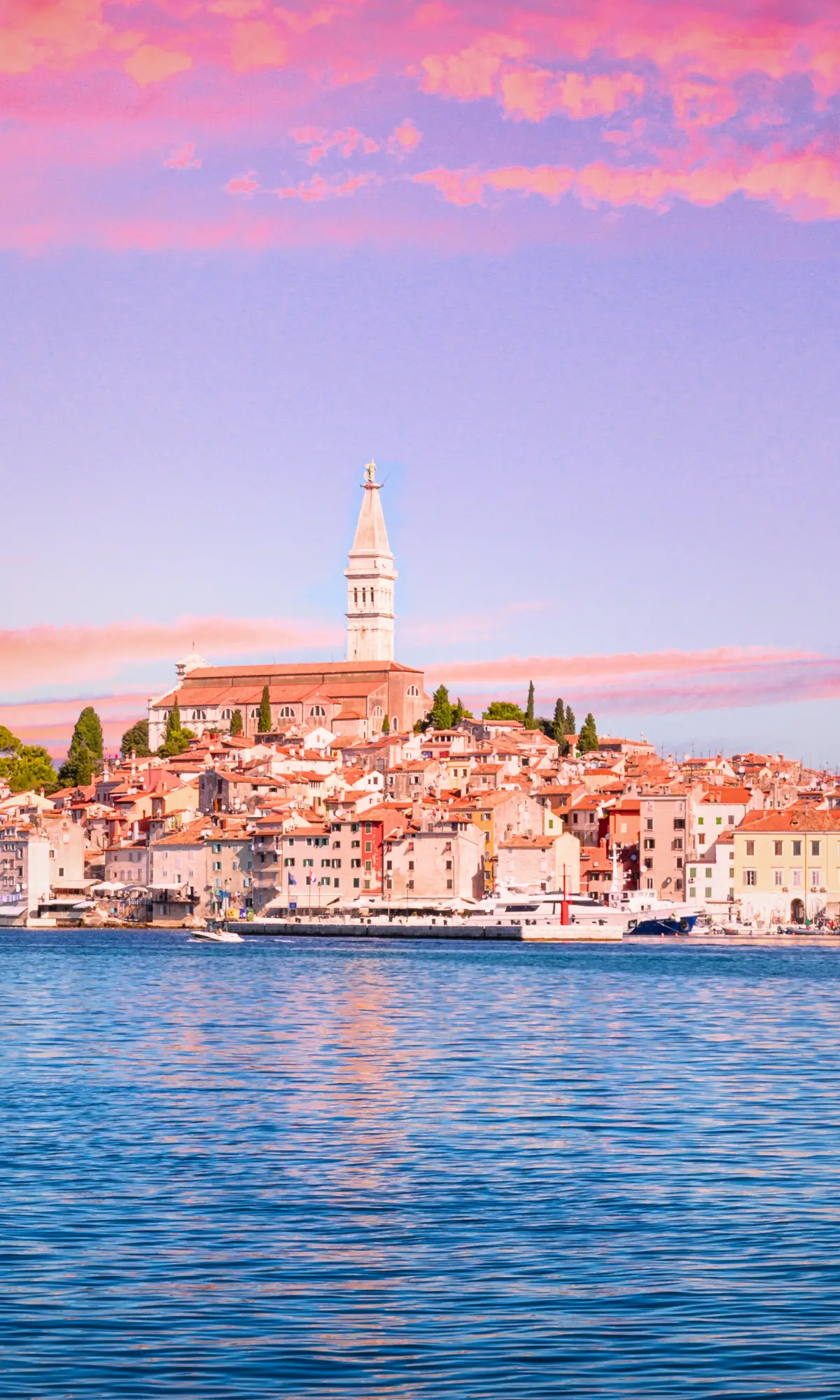 Colourful waterfront and church tower of Rovinj Old Town in Istria Croatia overlooking the Adriatic Sea at sunset.