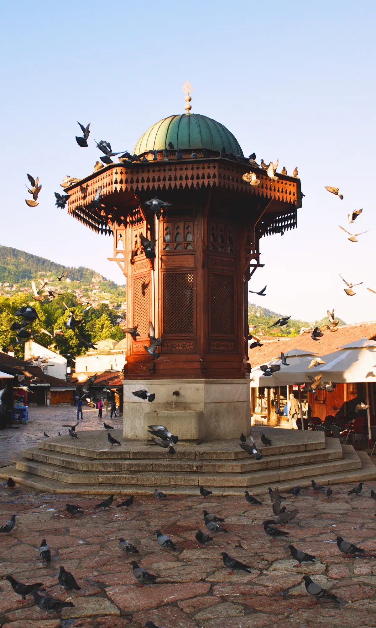 Sebilj fountain in Baščaršija Square with pigeons flying around in Sarajevo.
