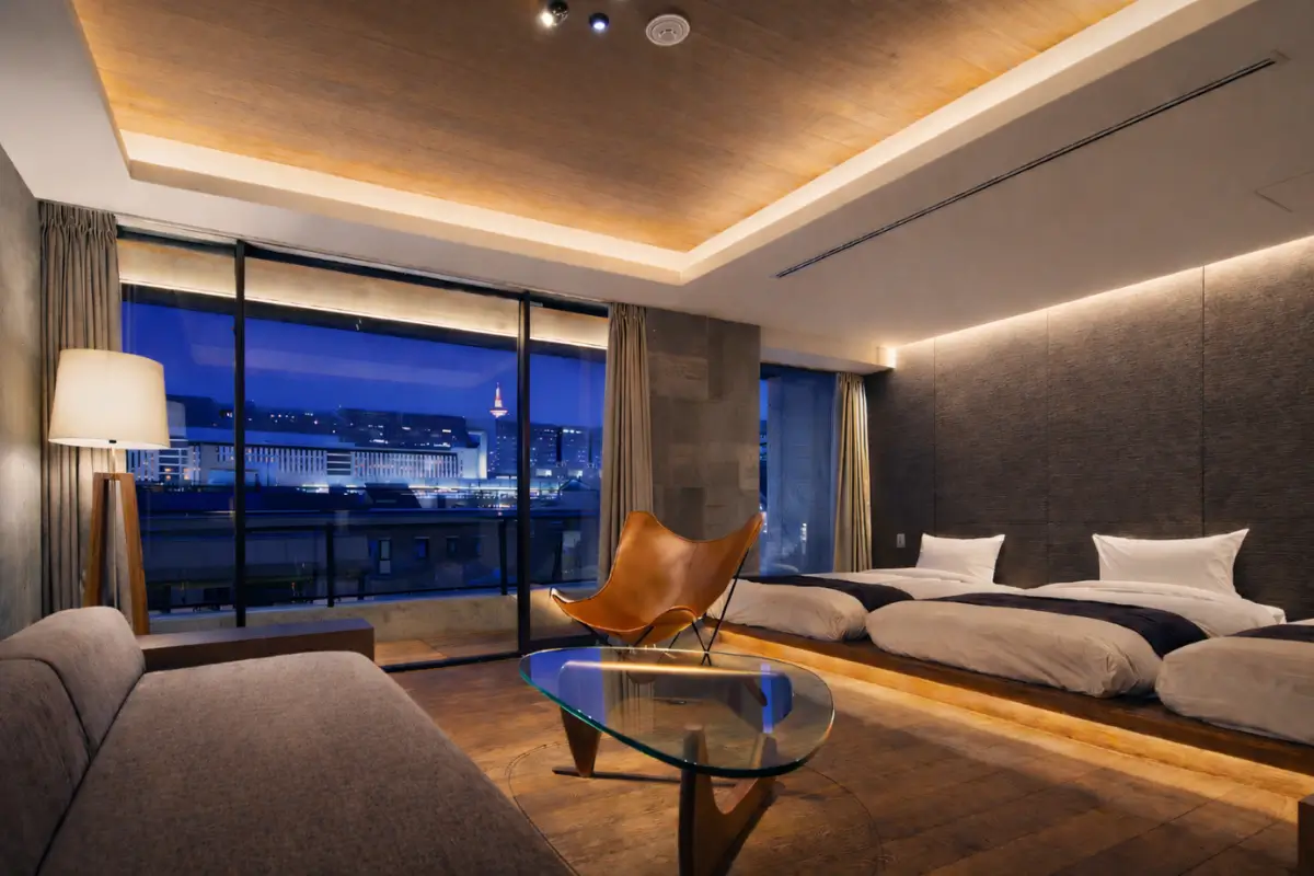 Modern room at 22 Pieces Kyoto with low beds, warm lighting, seating area, and large windows.