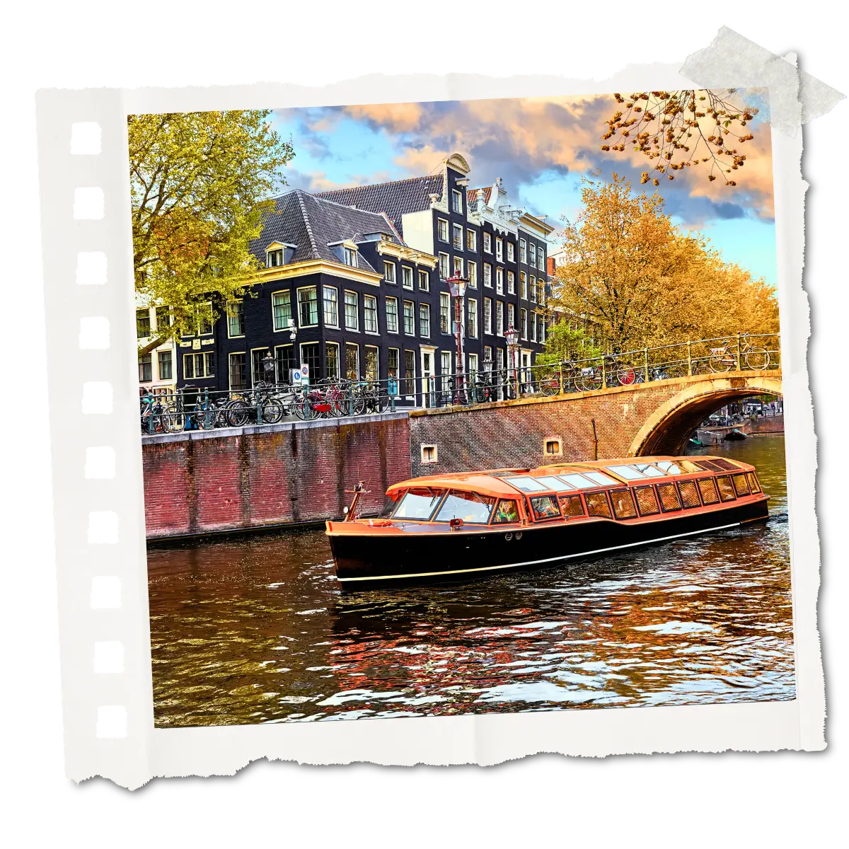 A canal boat passing under a bridge with historic buildings in Amsterdam.
