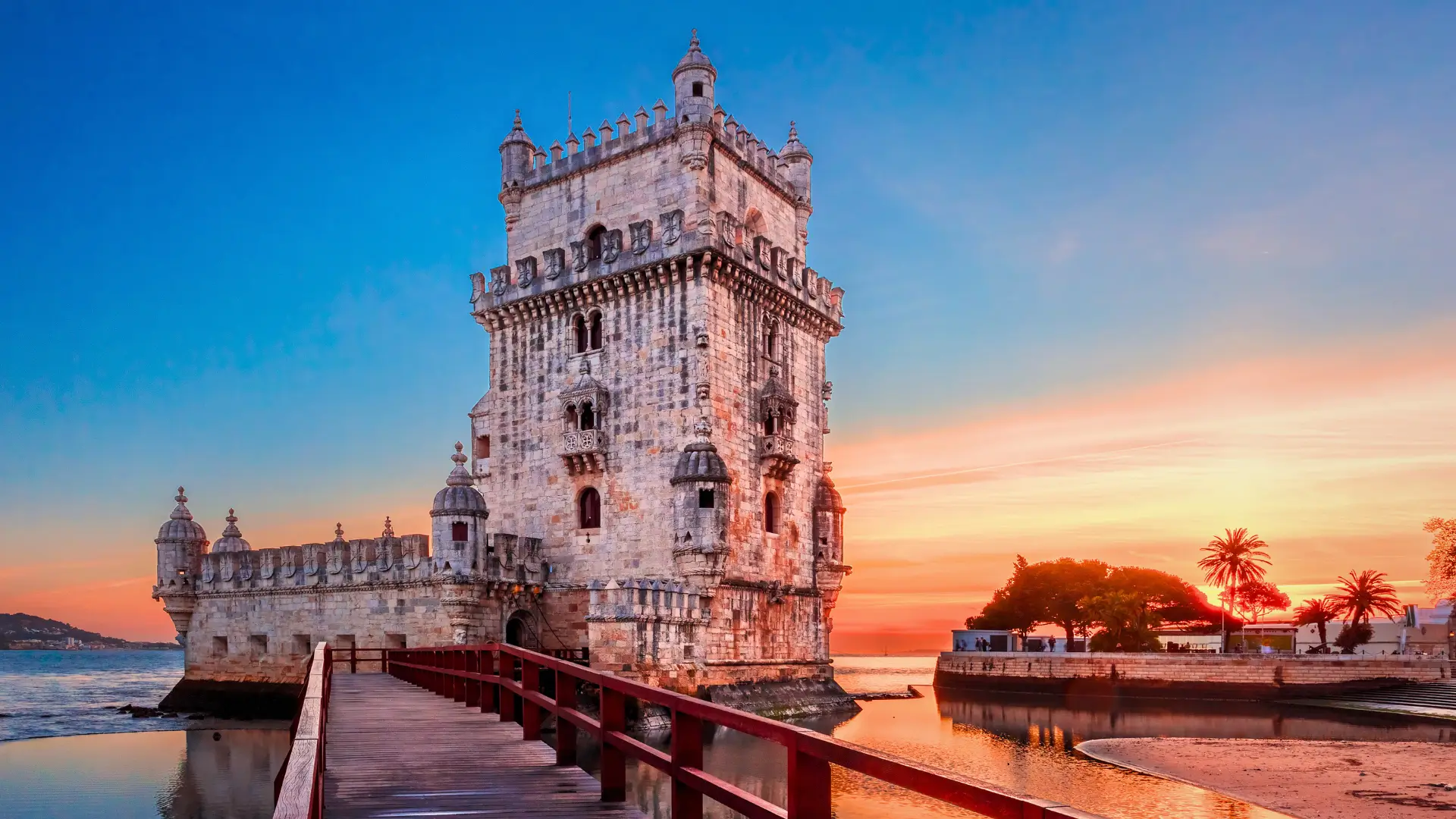 Belém Tower in Lisbon at sunset with warm light reflecting on the Tagus River in Portugal.