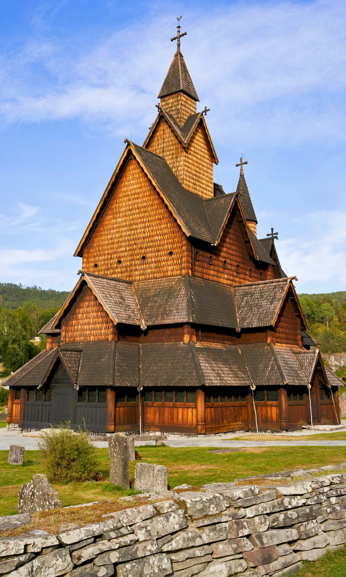Borgund Stave Church in Norway with layered wooden roofs and carved details against a blue sky.