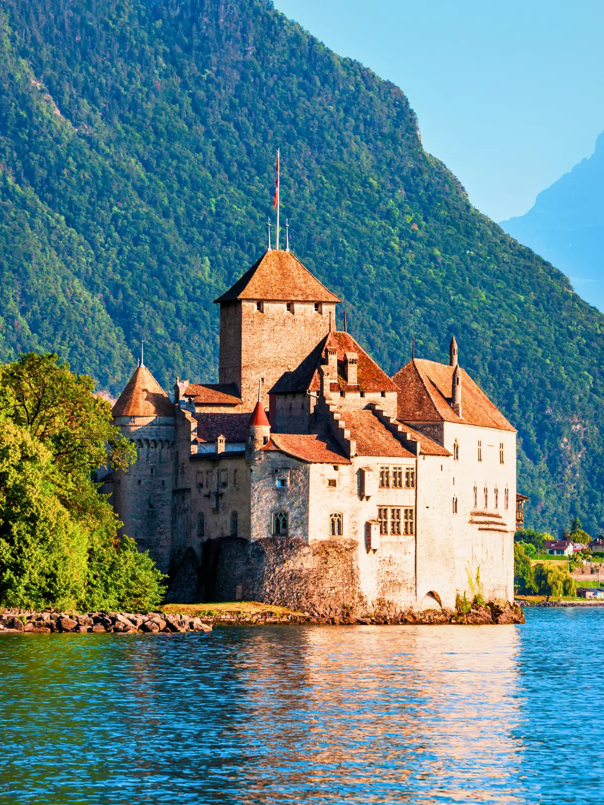 Château de Chillon sitting on Lake Geneva with mountains rising behind it.