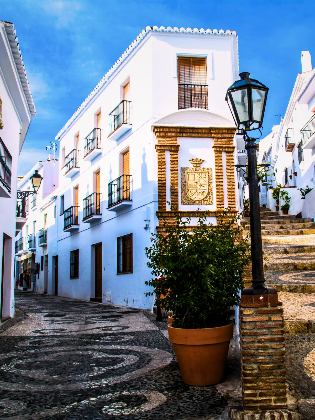Whitewashed street with steps and balconies in Frigiliana old town.