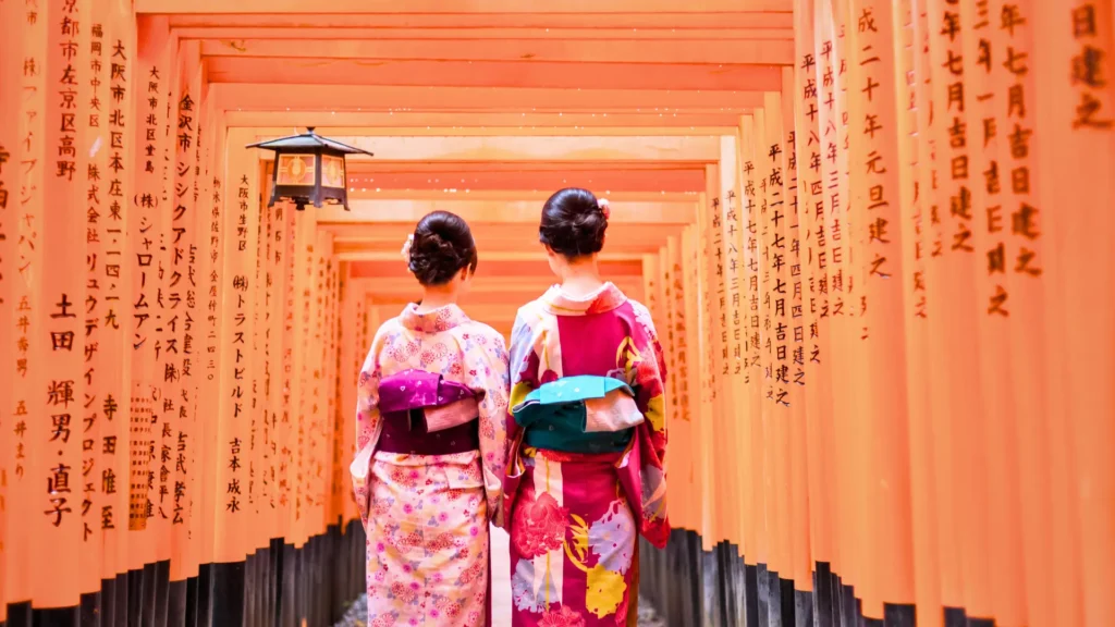 Two women in kimonos walking through the torii gates at Fushimi Inari Taisha in Kyoto.
