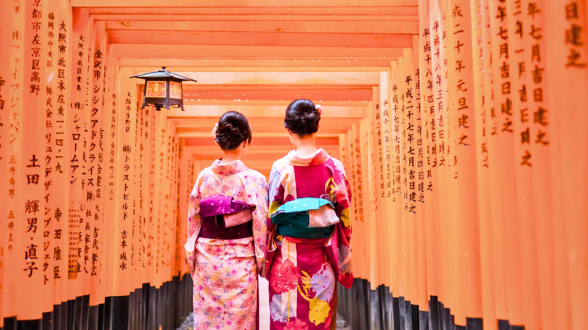 Two women in kimonos walking through the torii gates at Fushimi Inari Taisha in Kyoto.