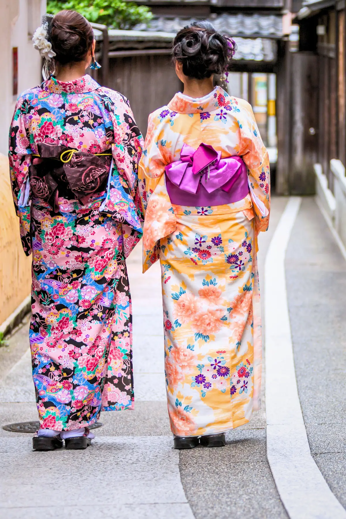 Two women in colourful kimonos walking through a narrow street in Gion, Kyoto.