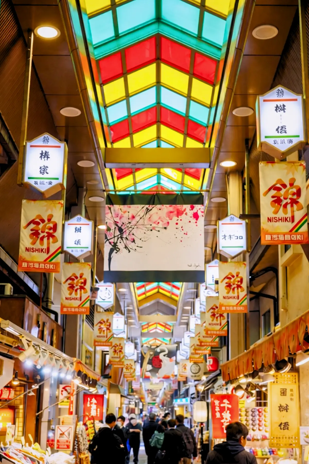 Busy covered street with food stalls inside Nishiki Market in Kyoto.