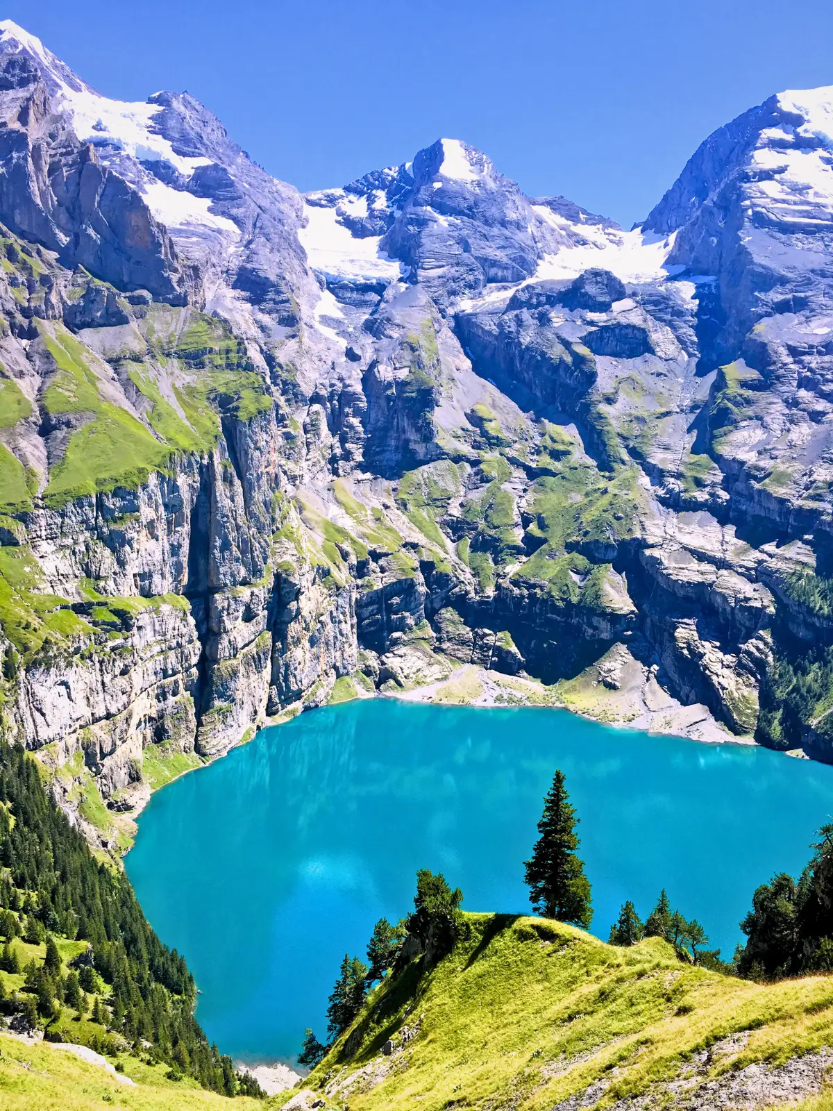 Turquoise Oeschinen Lake in Kandersteg surrounded by steep cliffs and alpine peaks.