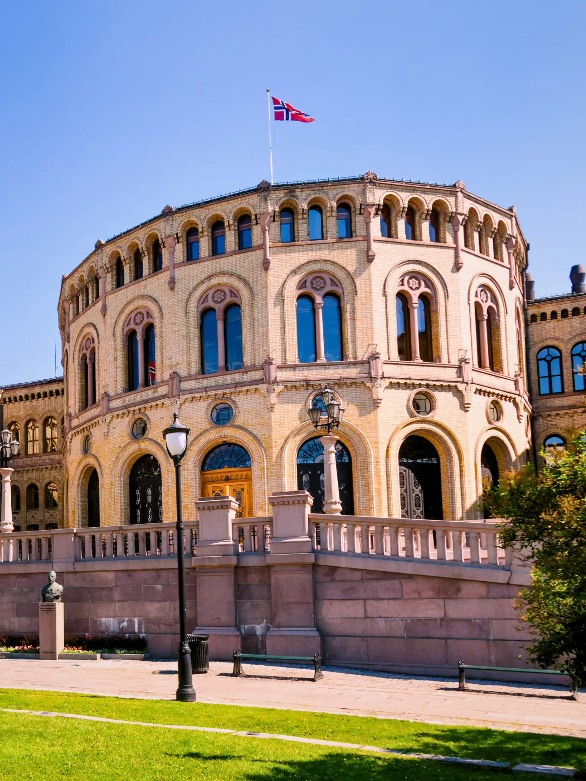 The Norwegian Parliament building in Oslo with a flag flying above the historic structure.