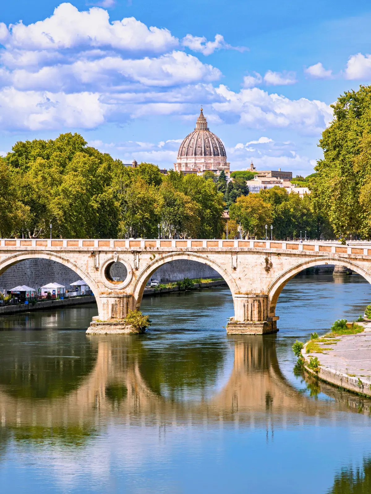 Ponte Sant’Angelo over the Tiber River with St Peter’s Basilica dome in the background in Rome.