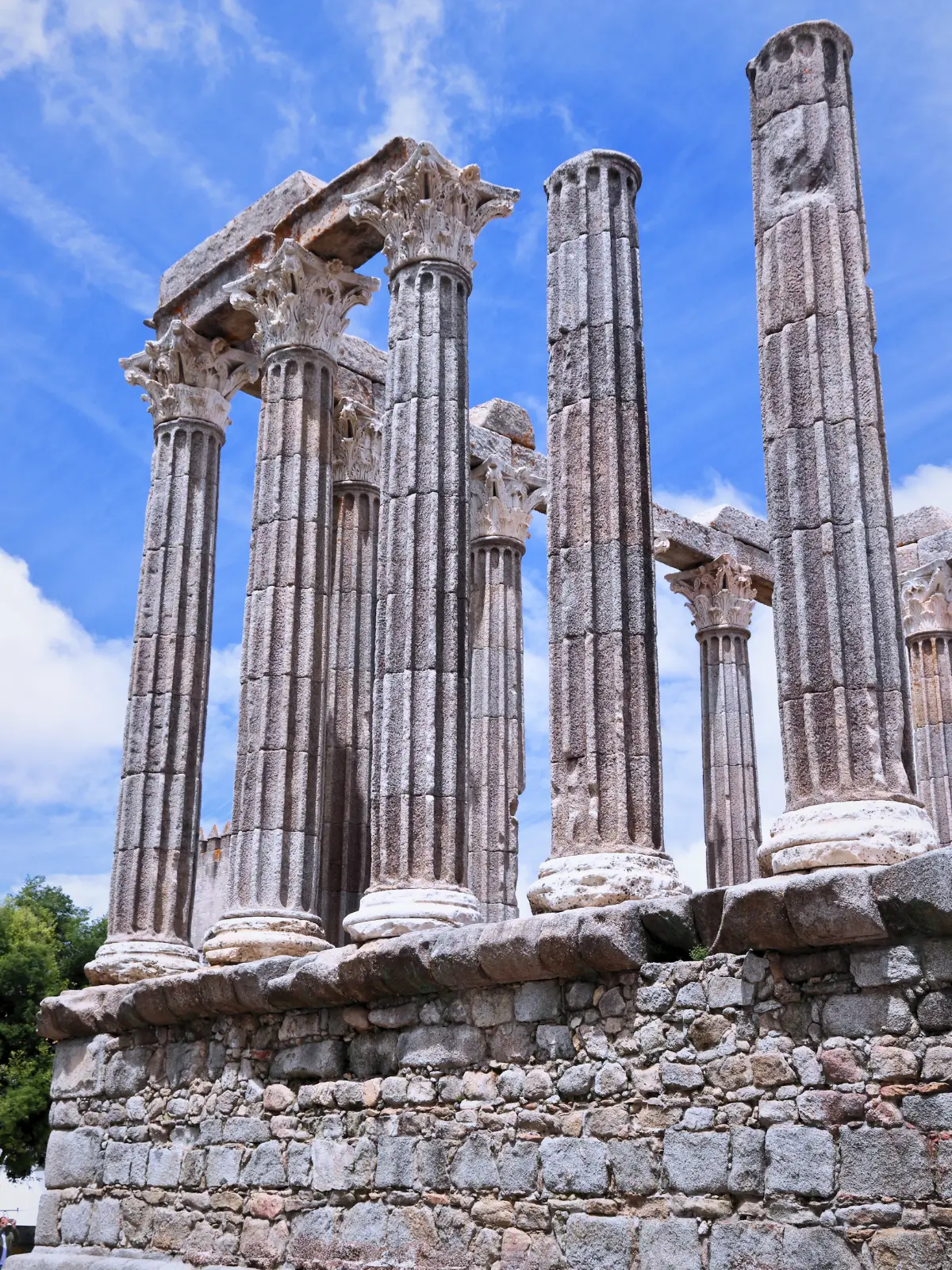 Ancient Roman temple ruins in Évora with tall stone columns standing against a blue sky in Portugal.