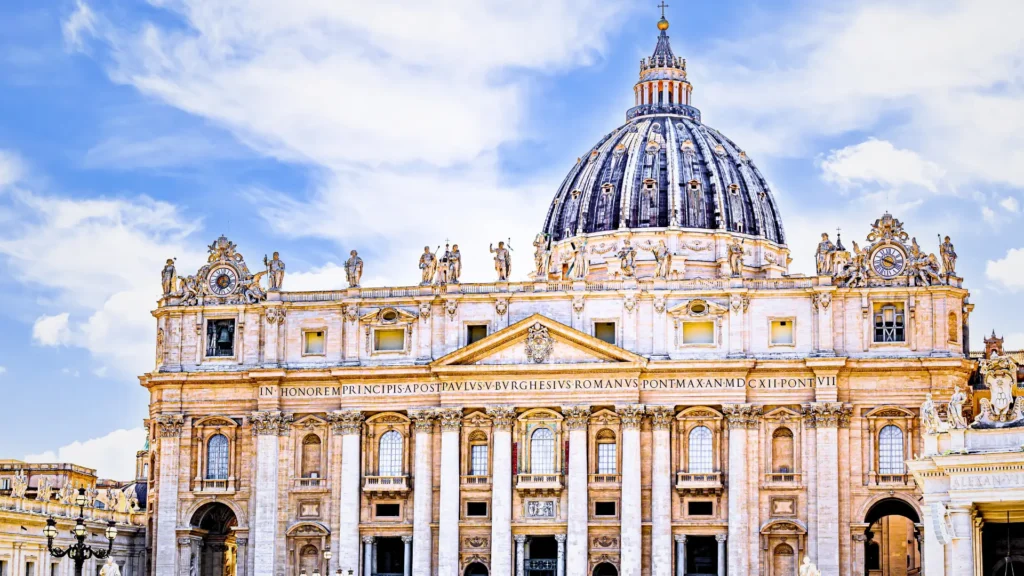 Front facade of St Peter’s Basilica with the central dome and statues above the colonnade in Vatican City.
