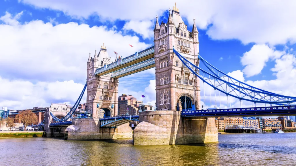 Tower Bridge in London spanning the River Thames with blue suspension elements and city backdrop.