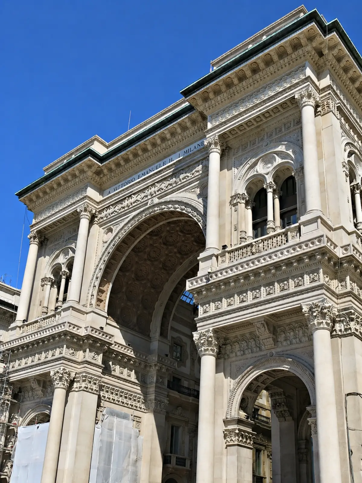 Galleria Vittorio Emanuele II archway against a clear blue sky.