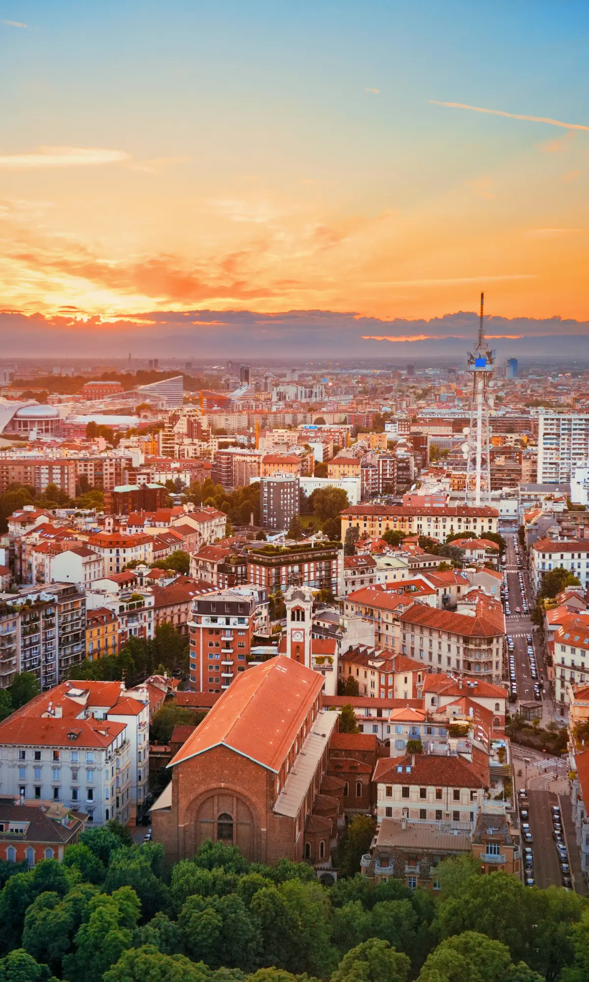 Aerial view of Milan skyline with historic buildings and warm sunset light over the city.