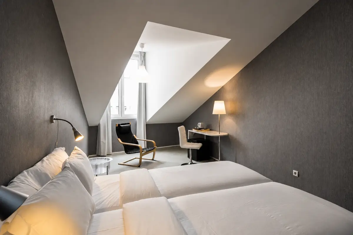 Twin guest room with grey walls, white bedding and a small desk.