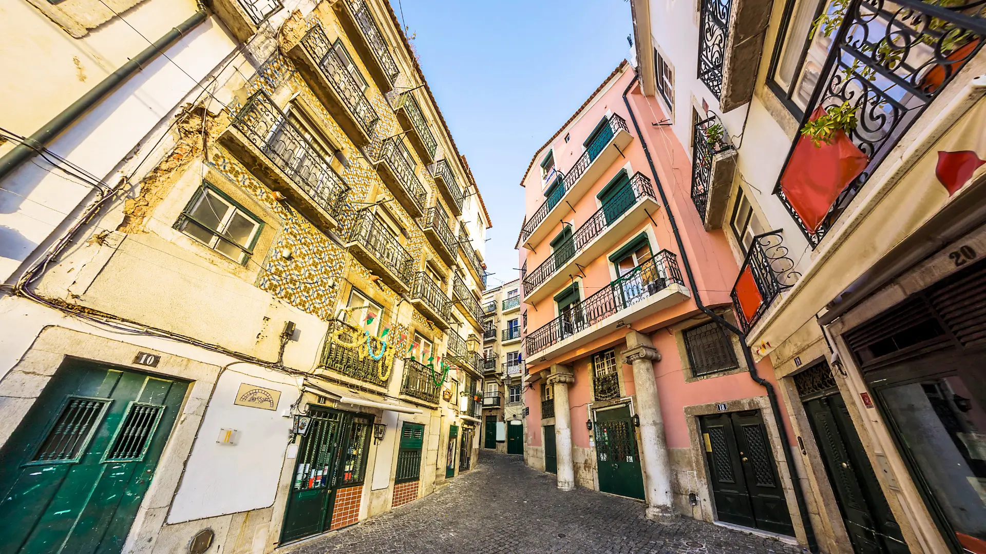 Narrow cobblestone street lined with traditional tiled and colourful buildings in Alfama.