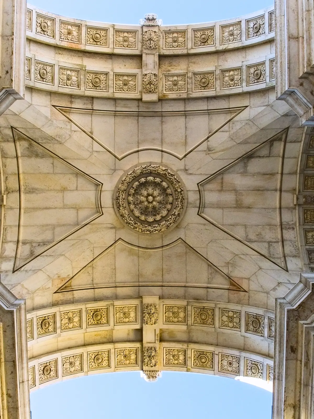Underside view of the stone vaulted ceiling and carved rosette of the Arco da Rua Augusta.