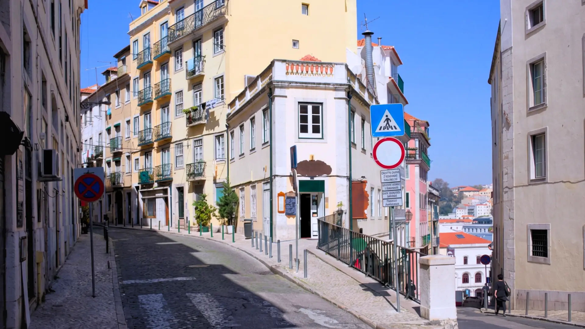 Sloping cobblestone street in Bairro Alto with traditional apartment buildings and traffic signs.