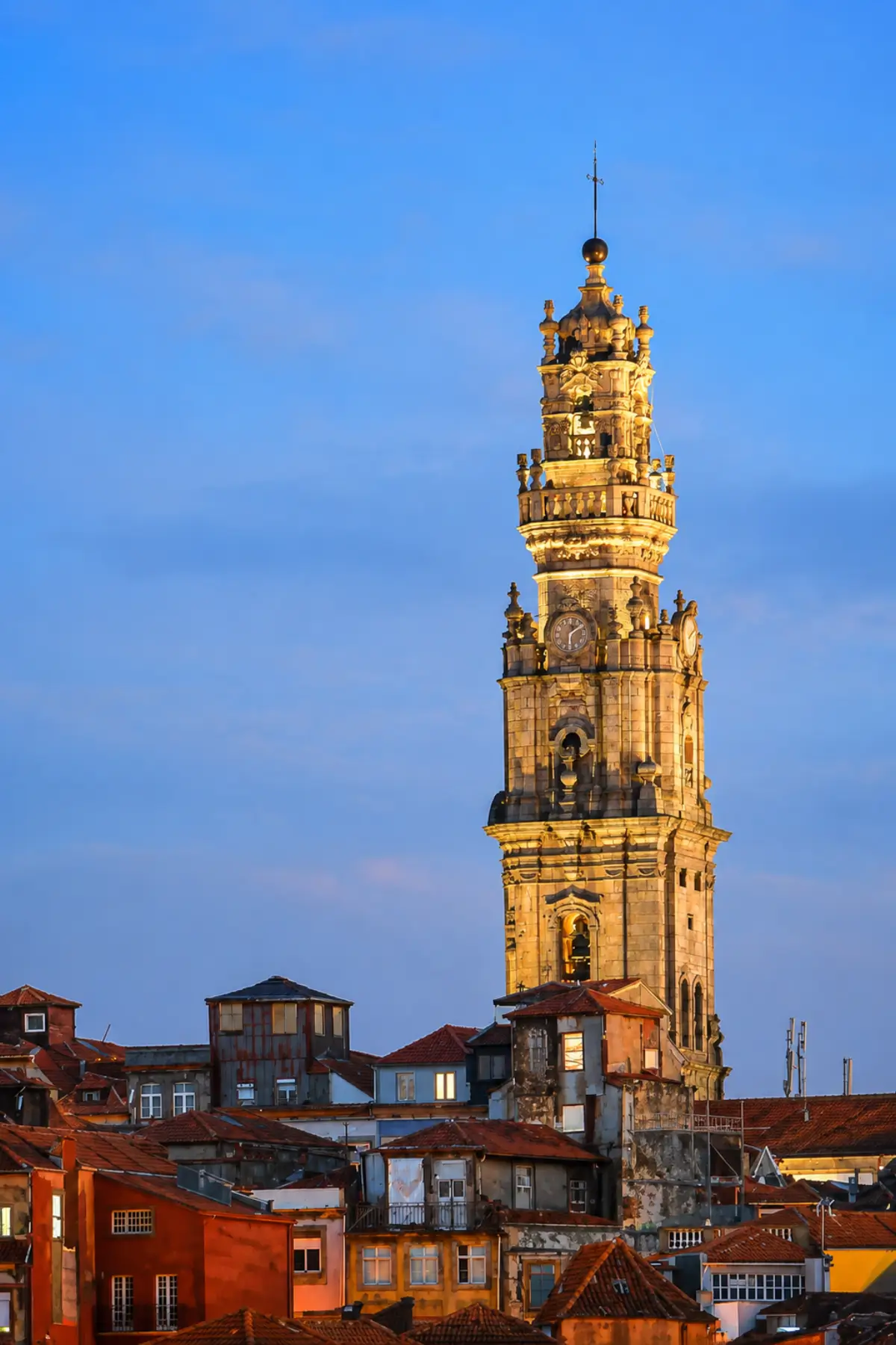 Illuminated Clérigos Tower above Porto rooftops in the evening.